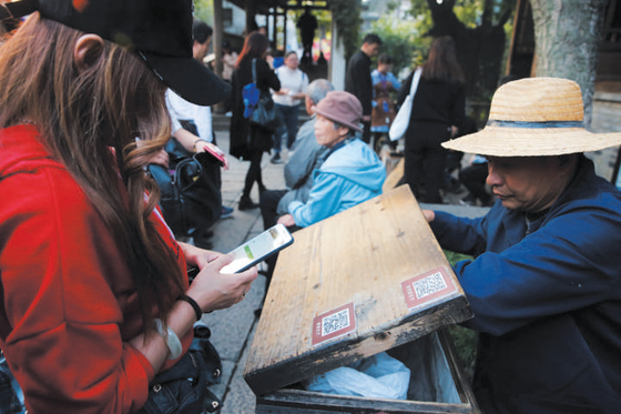 10月23日，乌镇西栅景区，卖老冰棍儿的商贩用二维码收款。新京报记者 侯少卿 王嘉宁 摄